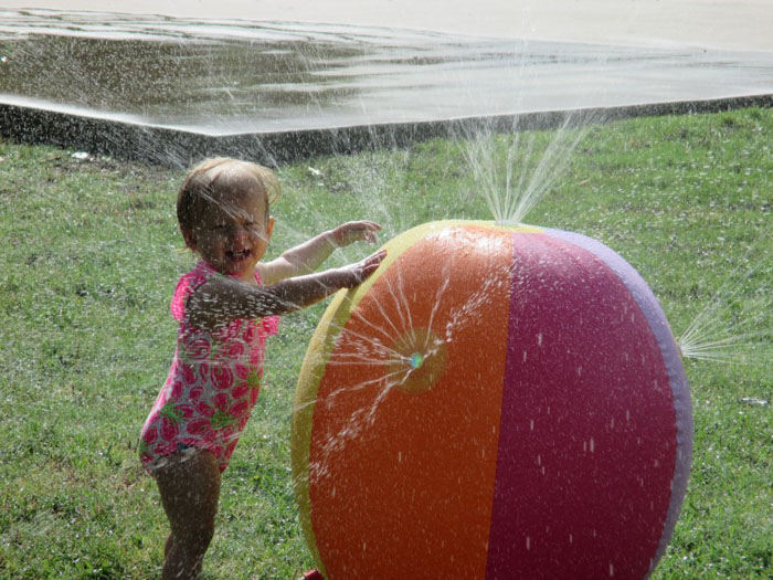 young girl taking a bath outside with a water fountain